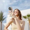 Happy woman holding a silver portable ice-cool relief fan with a power bank feature.